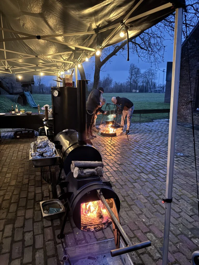 Smoker met brandend vuur onder een verlichte tent op locatie