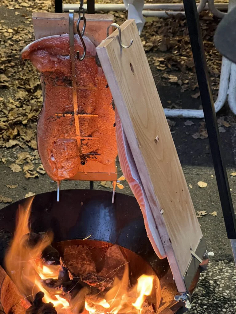 Zalm op een houten plank boven open vuur