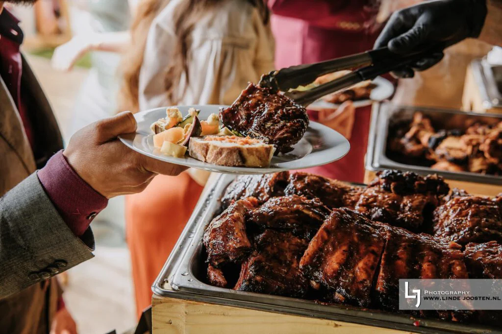 Ribs worden geserveerd aan een gast tijdens de bruiloftbarbecue